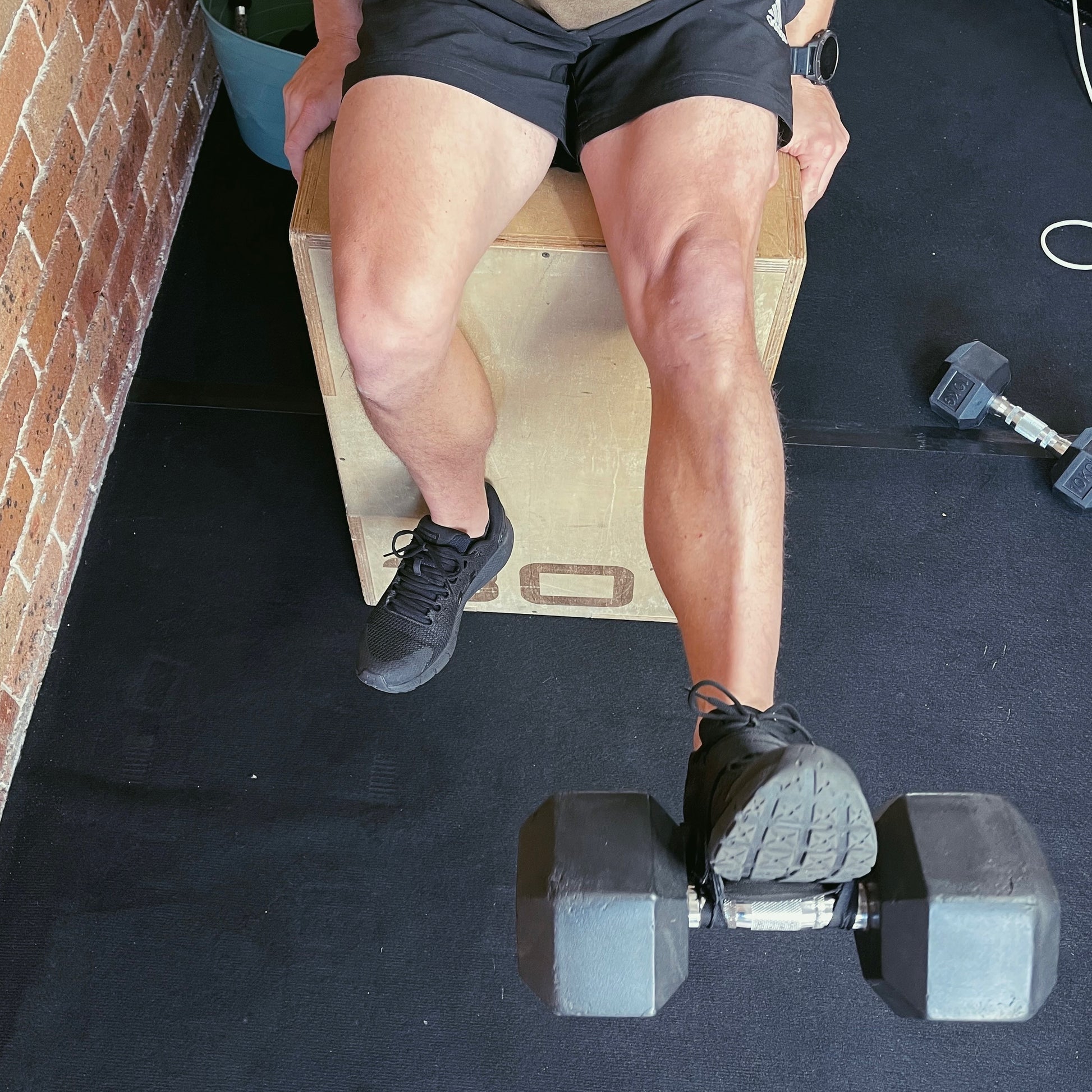 Guy with a perfect physique using a bb foot strap for training legs on leg day. Heavy dumbbell used to perform a leg extension to help with muscle growth and muscle definition. Leg exercises are a key part of any training program. When lower body exercises are being performed be sure they are done with your dumbbells and the bb foot strap 